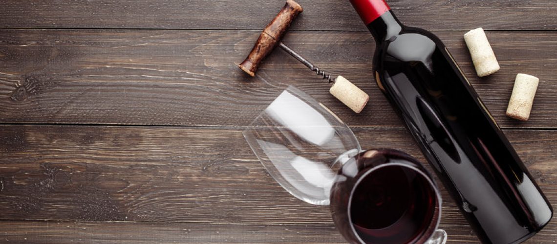Glass bottle of wine with corks on wooden table background.Top view with copy space